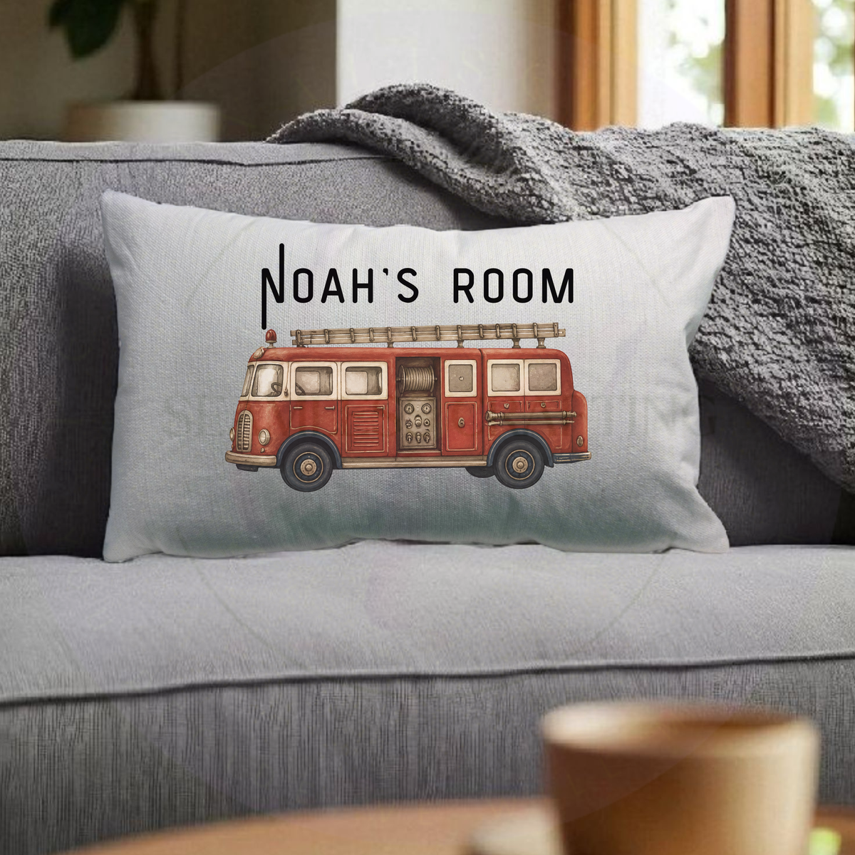 Personalised children's fire engine cushion displayed on grey sofa