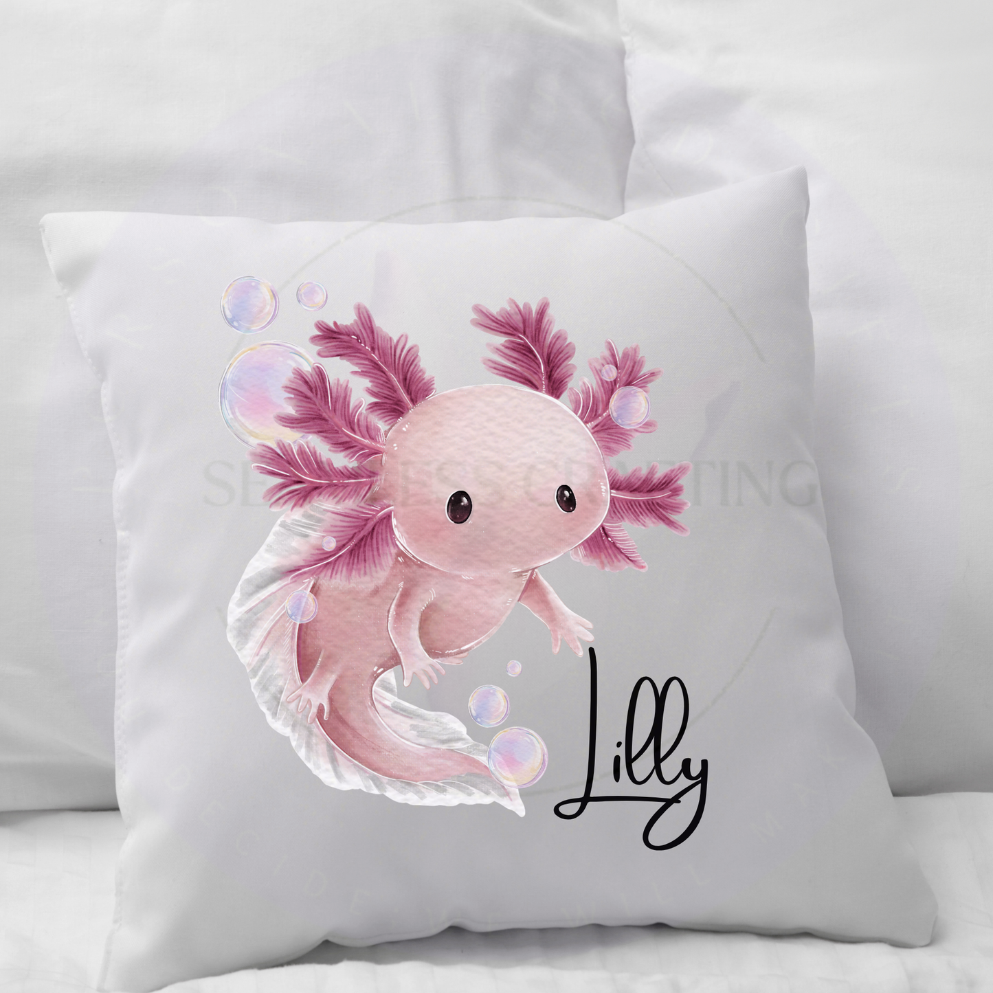 Two personalised axolotl cushions on a sofa showing black and pink colour options with names Isabelle and Lilly
