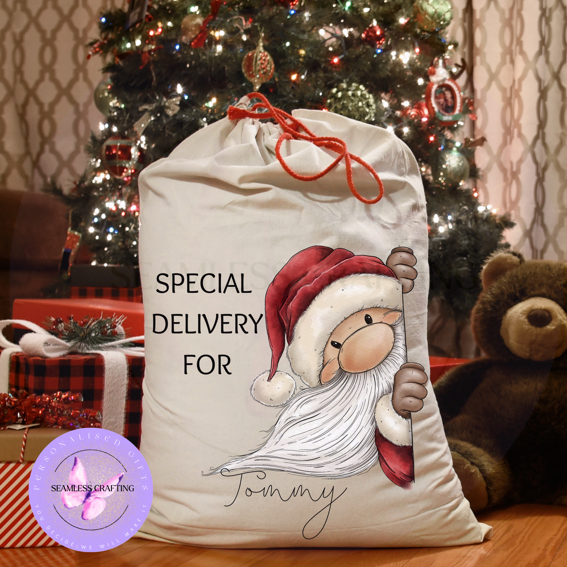 Large personalised Santa sack with peeking Santa design beside Christmas tree